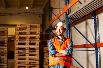 Fototapeta na wymiar Happy young worker in protective uniform in front of wooden pallets