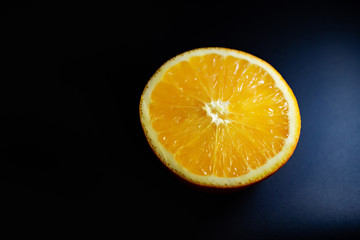 juicy natural orange slice lies on a black background