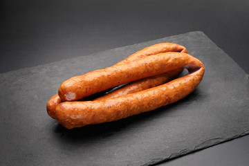 Rings of smoked pork sausage on a dark background.