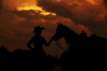 Fototapeta na wymiar cowgirl and horse sunset silhouette