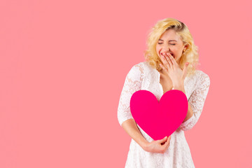 Studio portrait of a laughing young woman holding pink heart with eyes closed, romantic love, dating and Valentine's Day concept
