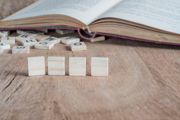 four blank cubes on wooden table against old book