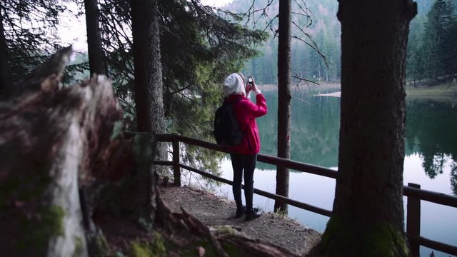 Beautiful view of back woman with backpack standing near lake take picture travel vacation tourism traveler reflection scenic attraction condition close up slow motion