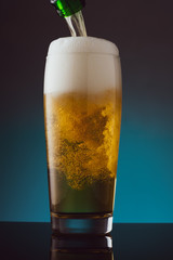 Glass of beer with foam on blue background