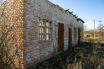 Old brick ruined house with iron doors and broken windows
