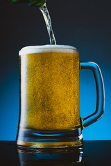 Glass of beer with foam on blue background