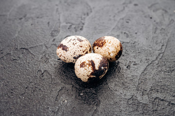 Quail eggs on a black background. Several quail eggs lie on a black stone background
