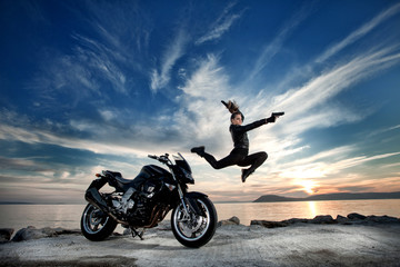 Fototapeta na wymiar Woman with the Guns Jumping over a Motorcycle