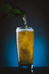 Glass of beer with foam on blue background	