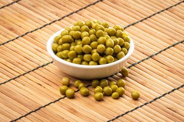 Canned green peas in the bowl on wood background