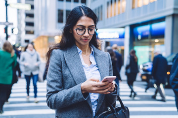Busy ethnic female walking with smartphone