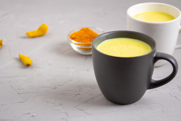 Two cups with Golden milk on a gray background