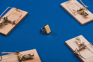 Selective focus of jewellery ring with wooden mouse traps on blue background