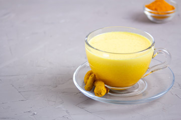Golden milk in a glass gray cup on a gray background