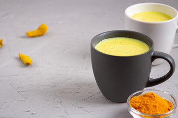 Two cups with Golden milk on a gray background