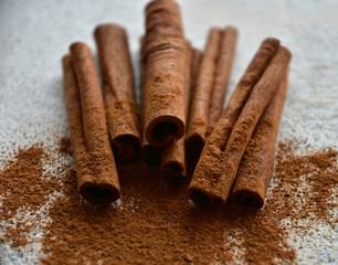 Cinnamon sticks and cinnamon powder on a stone background. Close-up. Side view. Natural light.