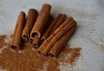 Cinnamon sticks and cinnamon powder on a stone background. Close-up. Side view. Natural light