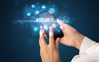 Female hand holding smartphone with ASP.NET inscription, modern technology concept