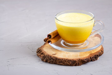 Golden milk in a glass gray cup on a gray background