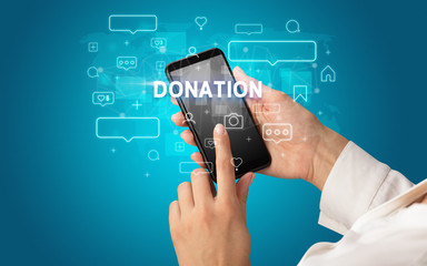 Female hand typing on smartphone with DONATION inscription, social media concept