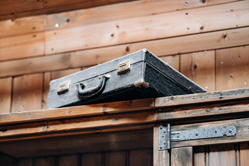 An old battered suitcase on a shelf in the dust. Vintage travel bags are on a shelf. Retro bulky Luggage. Image done in grunge style on rough dirty texture background