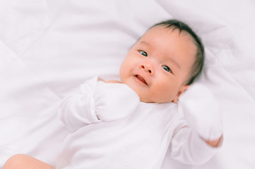 Smiling baby boy lying on a  white bed, Family morning at home,Children hygiene.