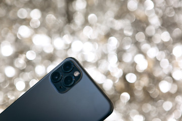 Modern phone with a triple camera on a silver background.