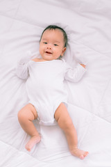 Smiling baby boy lying on a  white bed, Family morning at home,Children hygiene.