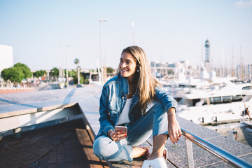 Fototapeta premium Cheerful lady using video call on smartphone relaxing at waterside