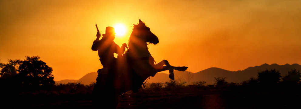 Silhouette cowboy riding horseback in farm at sunset, panorama landscape