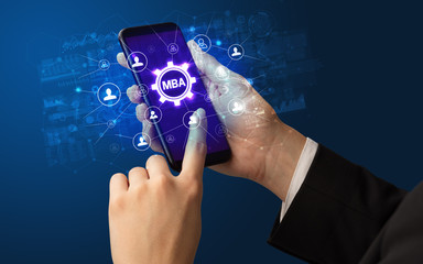 Female hand holding smartphone with MBA abbreviation, modern technology concept