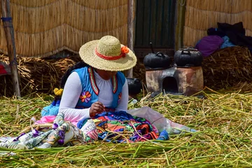 Foto op Canvas A women sewing artisanal clothes on a flooding island on lake titicaca in Peru © Nicole