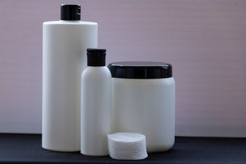 Mockup. White bottles for shampoo and masks for hair or other beauty items. on a black and white background. With a black cover. Red ribbon and heart, and gift.