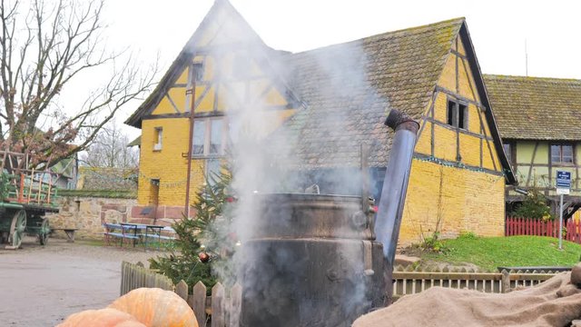Olla de verdura cocin&aacute;ndose en el exterior de una granja de fachada amarilla