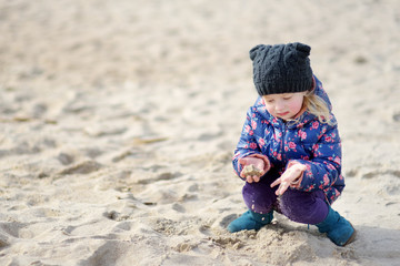 Adorable girl playing by the ocean on cold winter day