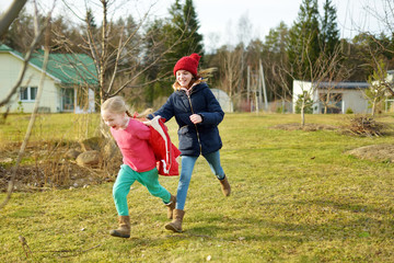 Two young sisters having fun together on beautiful spring day. Active family leisure with kids. Family fun outdoors.
