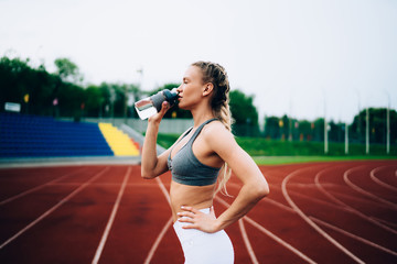 Athletic woman drinking water during break