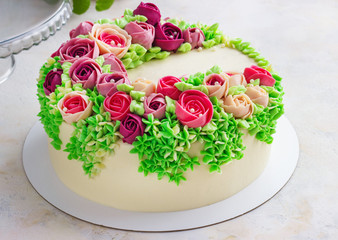Bright festive white cake with bright flowers made of cream, a wedding cake, for a woman.