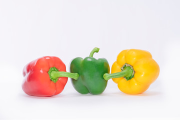 Fresh red, green and yellow bell peppers on a light background