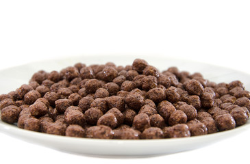 dry breakfast in a plate on a white background. Chocolate balls.