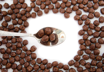 chocolate balls and a spoon with balls. dry breakfast on a white background. View from above.