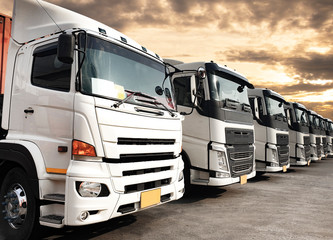 Naklejka premium Row of Semi TrailerTrucks Parked with The Sunset Sky. Shipping Container Trucks. Engine Diesel Trucks. Lorry Tractor. Industry Freight Trucks Logistics Cargo Transport. 