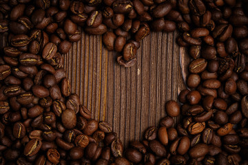 Abstract heart made from coffee beans on a background of burnt wooden board