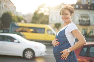 Pregnant Woman Walks Outdoors Through Urban Street In Sunny Day