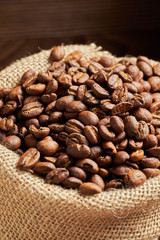 roasted coffee beans in a knitted bag on a wooden background. Vertical.