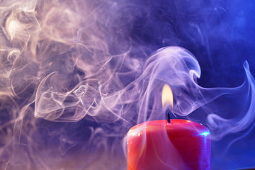 Red candle with smoke and flame photographed in the studio with color foils before the flashes