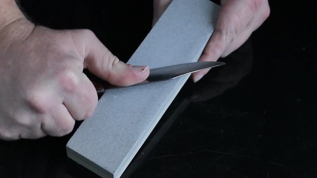 knife sharpening Whetstone on background of black boards.