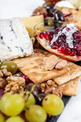 Food Platter With Truffle Cheese, Duck Breast, Brie Cheese, Pecan Nuts, Pomegranate Seeds, Grapes, Almonds, Honey, Olives and Crackers on White Marble Background