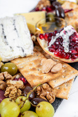 Food Platter With Truffle Cheese, Duck Breast, Brie Cheese, Pecan Nuts, Pomegranate Seeds, Grapes, Almonds, Honey, Olives and Crackers on White Marble Background