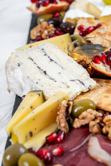 Food Platter With Truffle Cheese, Duck Breast, Brie Cheese, Pecan Nuts, Pomegranate Seeds, Grapes, Almonds, Honey, Olives and Crackers on White Marble Background